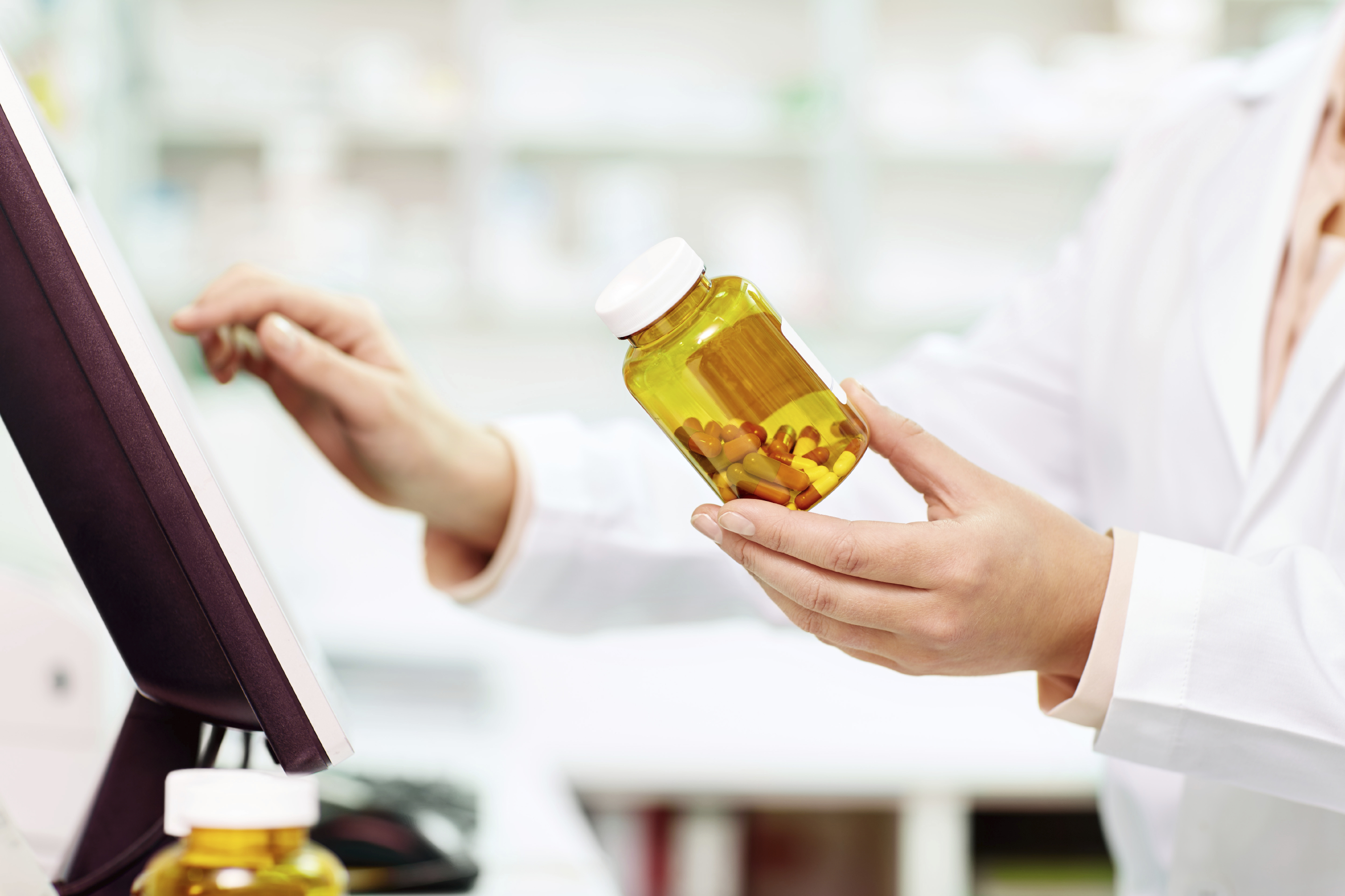 pharmacist-with-bottle-by-monitor.jpg