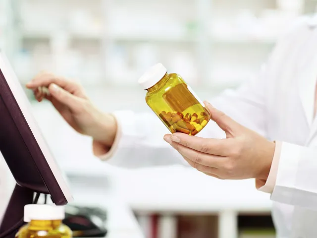 pharmacist-with-bottle-by-monitor.jpg