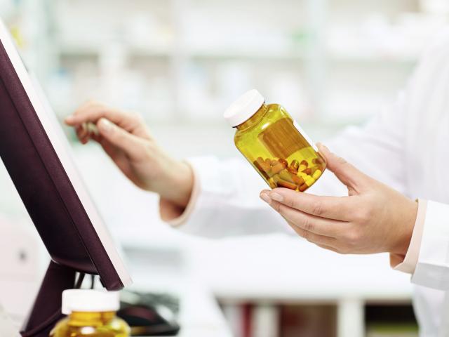 pharmacist-with-bottle-by-monitor.jpg